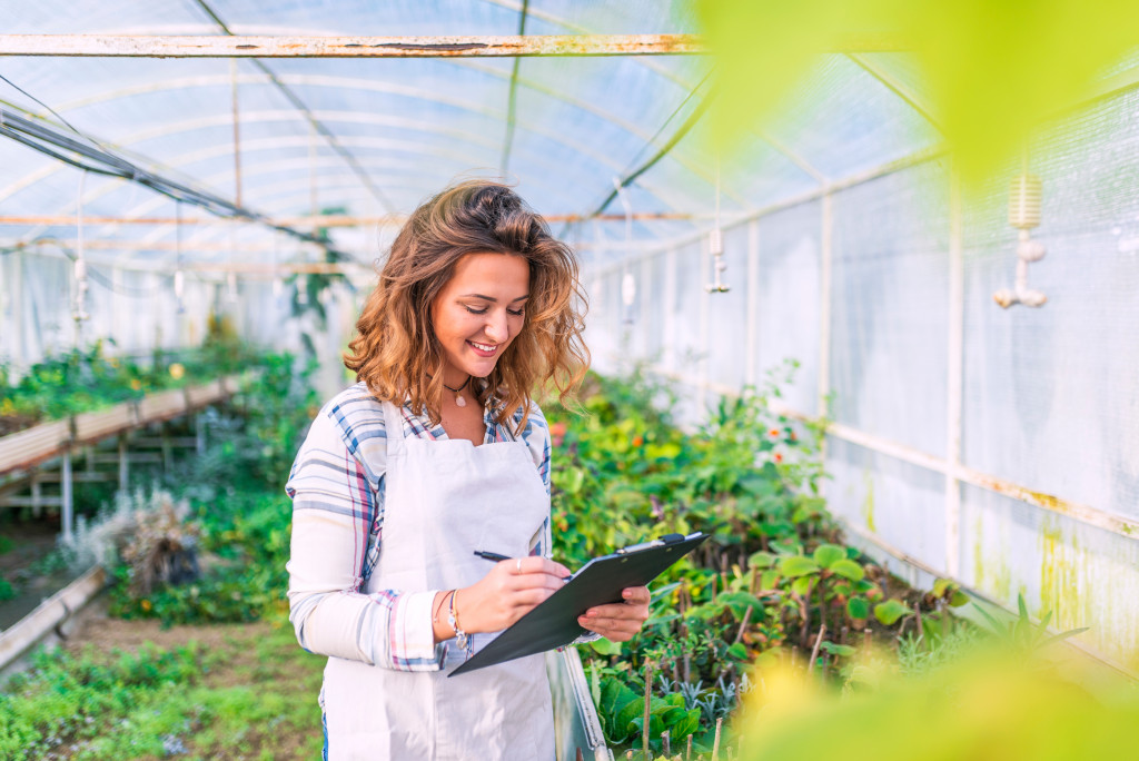 woman checking her list while inside her greenhouse farm