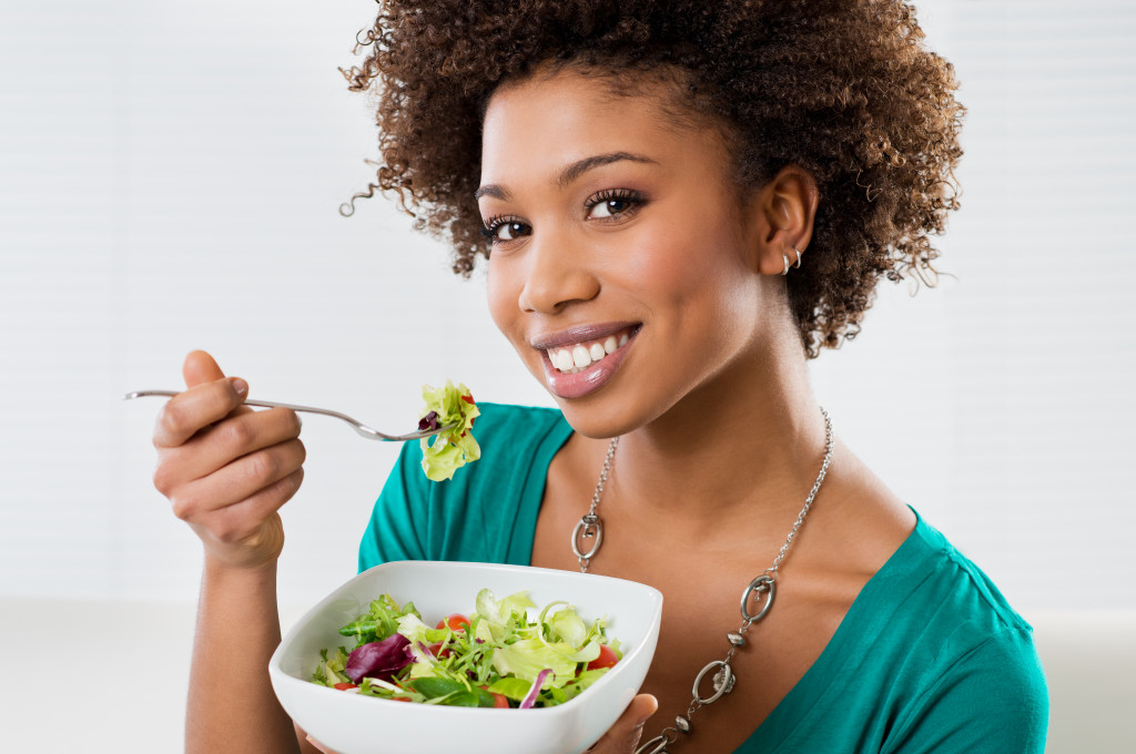 Smiling young woman enjoying her salad at home.