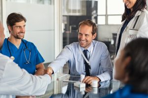 Doctors forming a partnership with a pharmaceutical representative. Sealing the deal in the office, shaking hands
